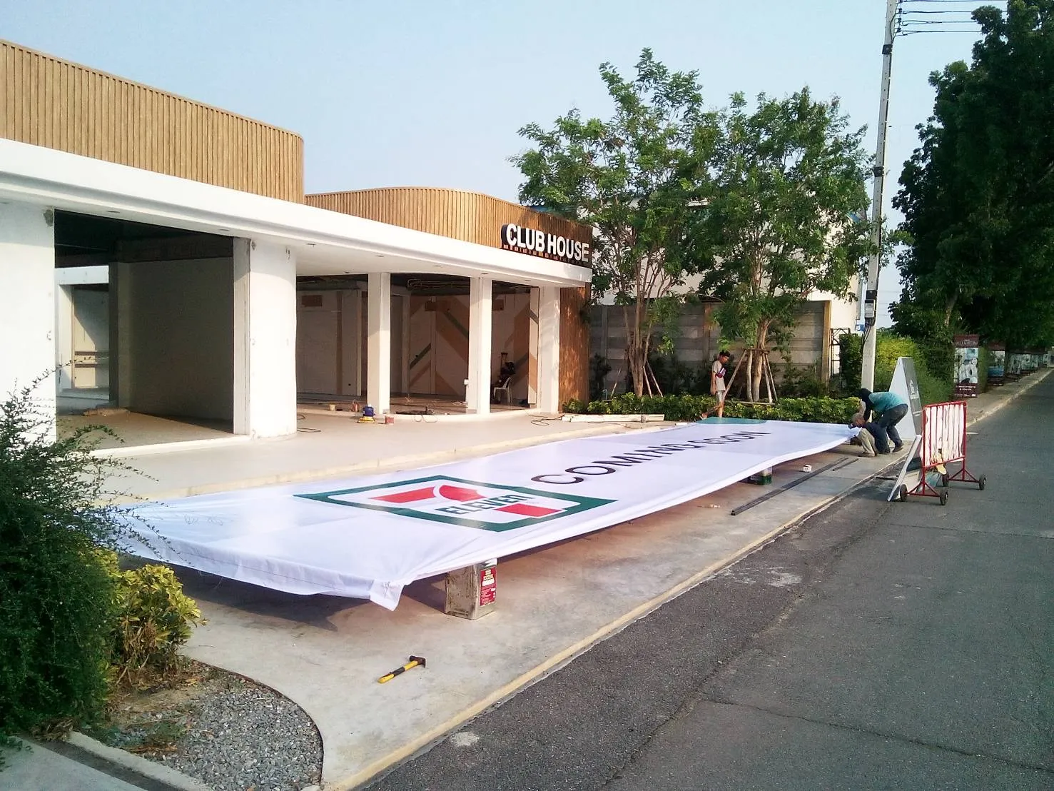 EXCESS team preparing a large 7-Eleven banner for on-site installation